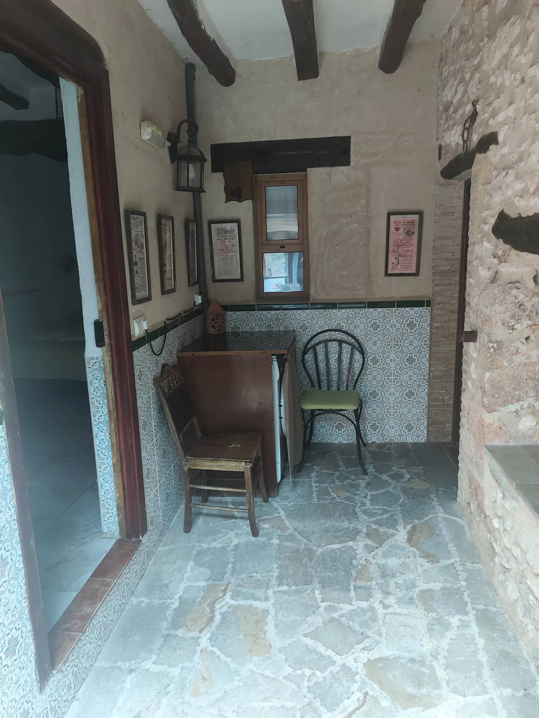 Zaguán de la casa con suelo de piedra, zócalo de azulejos y muebles antiguos