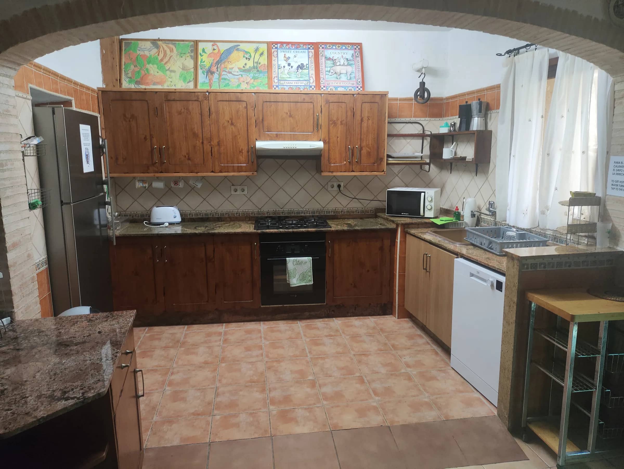 Cocina equipada con arco de ladrillo, horno, vitrocerámica, lavavajillas y frigorífico grande