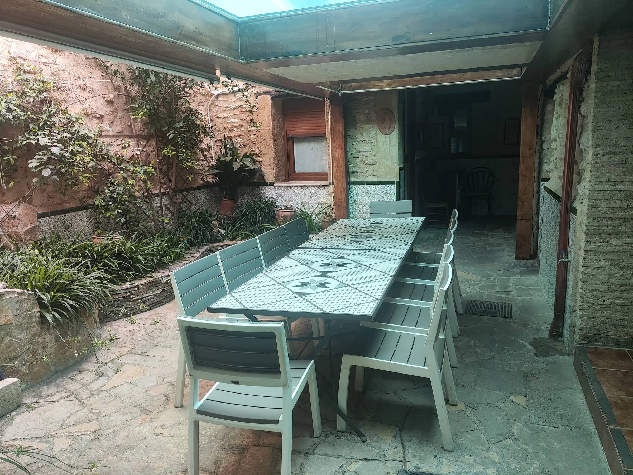 Patio interior de la casa rural con mesa larga para doce comensales bajo el suelo de cristal de la piscina