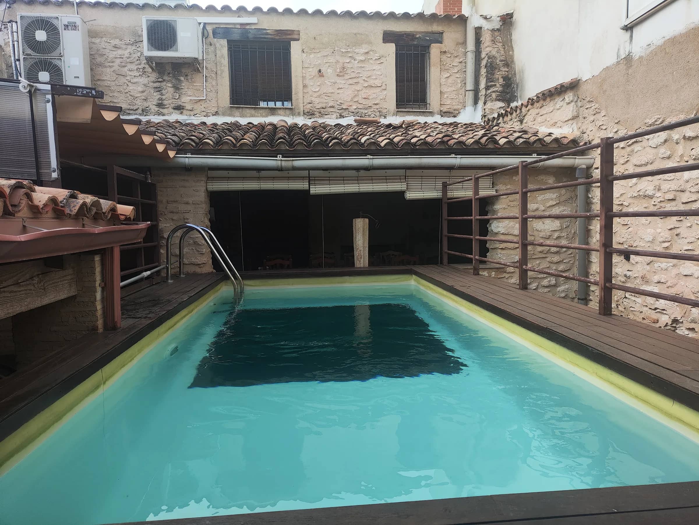 Piscina privada de la casa rural con tarima de madera y muros de piedra