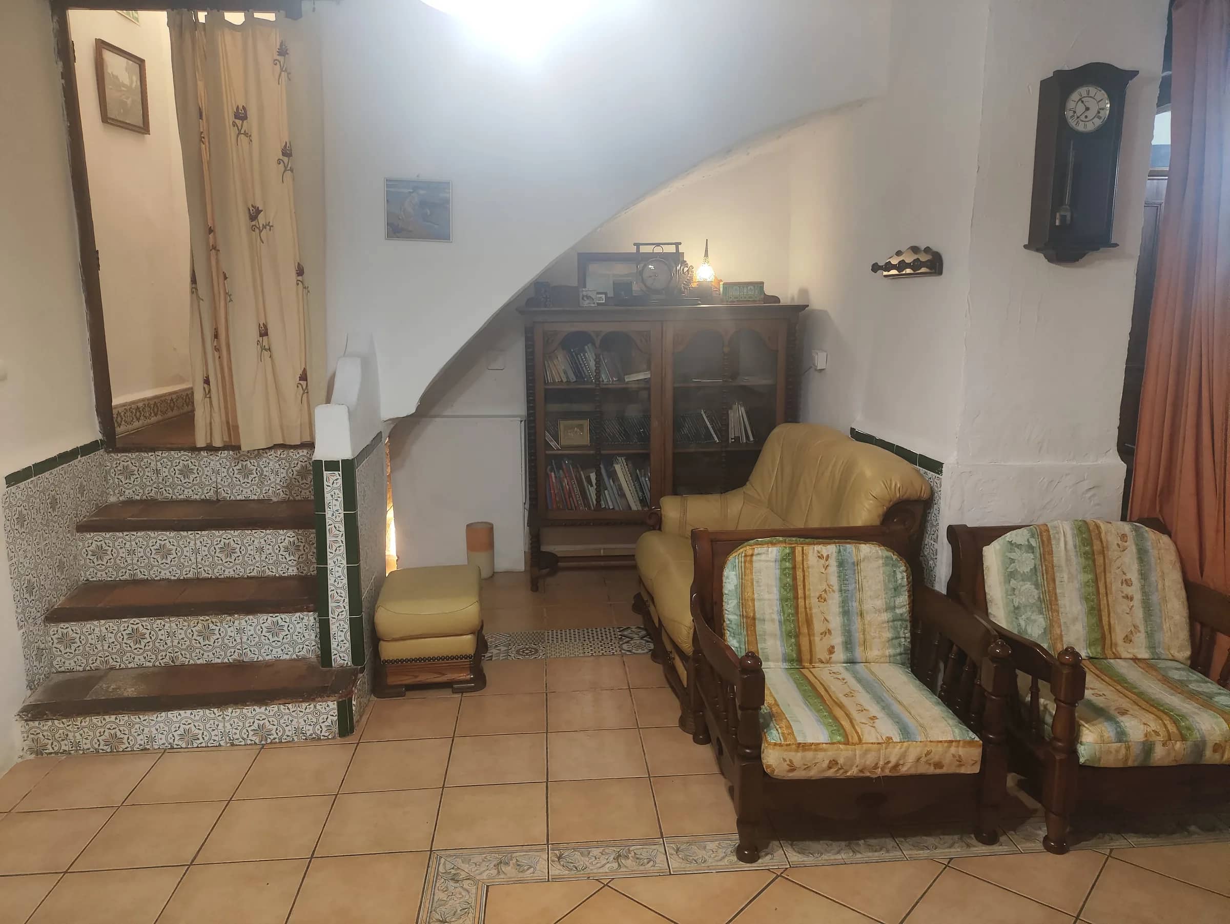 Rincón de lectura con biblioteca, butacas y escalera con zócalo de azulejos
